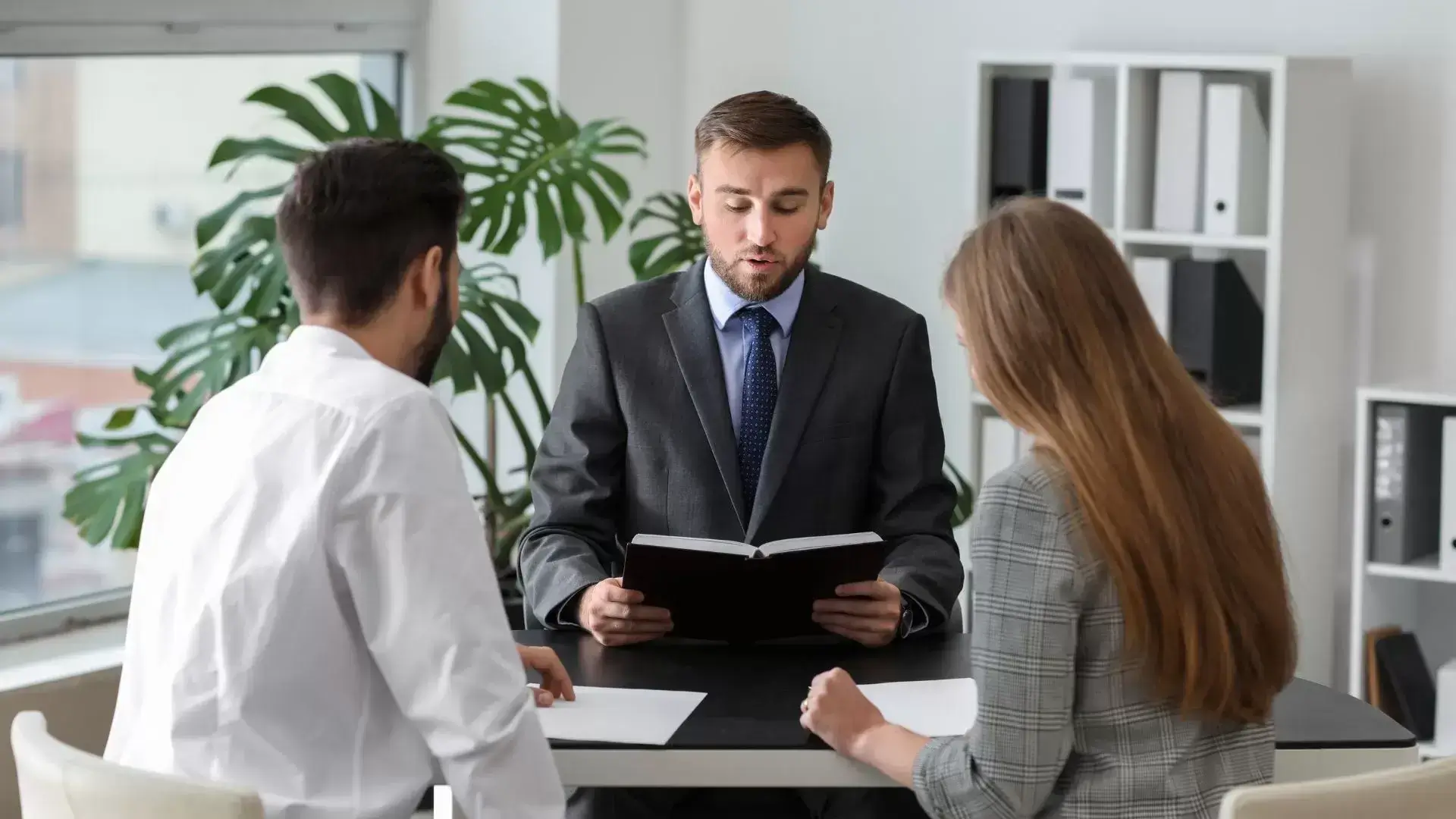 Couple attentively listening as their divorce therapist reads from a therapy guide during a Grief and Closure Therapy session at Mississauga Divorce Counselling Therapy, supporting healthy processing of relationship endings.