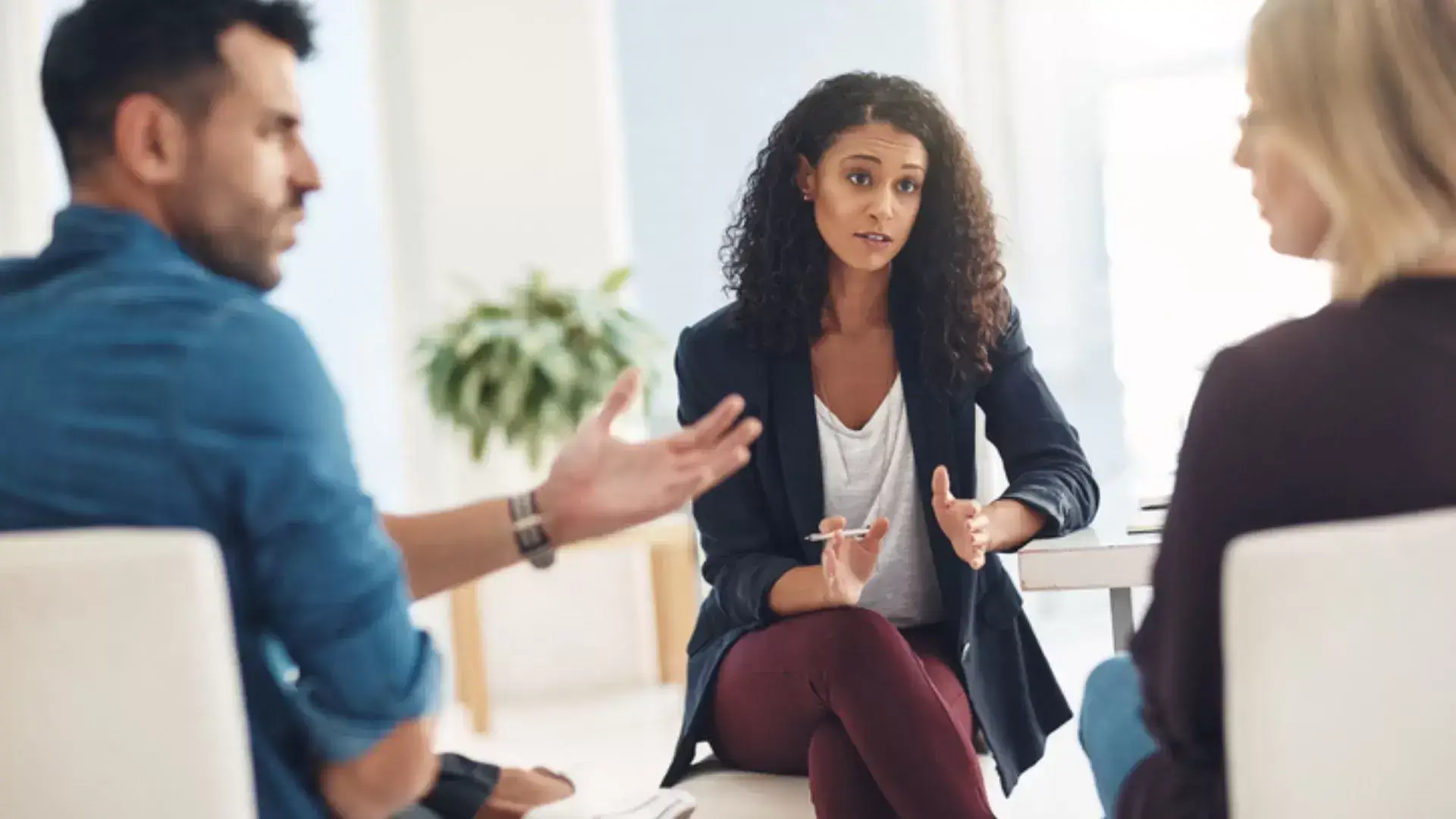 Man explaining his perspective to his partner while the divorce therapist engages them in conversation during a Motivational Interviewing session at Oakville Divorce Counselling Therapy, illustrating the MI process of exploring ambivalence, fostering collaboration, and supporting constructive dialogue in divorce counselling.